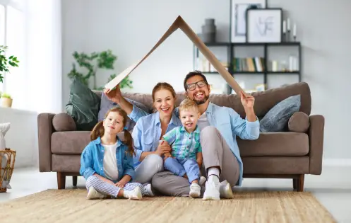 Family happily sitting on their living room floor, covered by a large box symbolizing the comprehensive health insurance cover provided by Prism Benefits Solutions